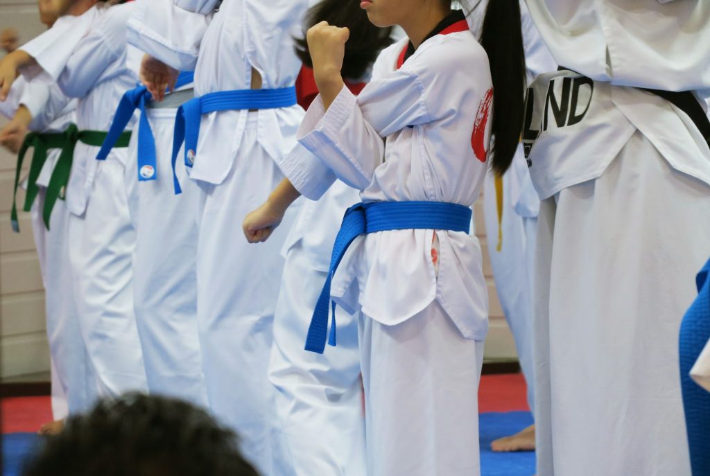 Group of Taekwondo students wearing white uniforms standing practice in class closeup background